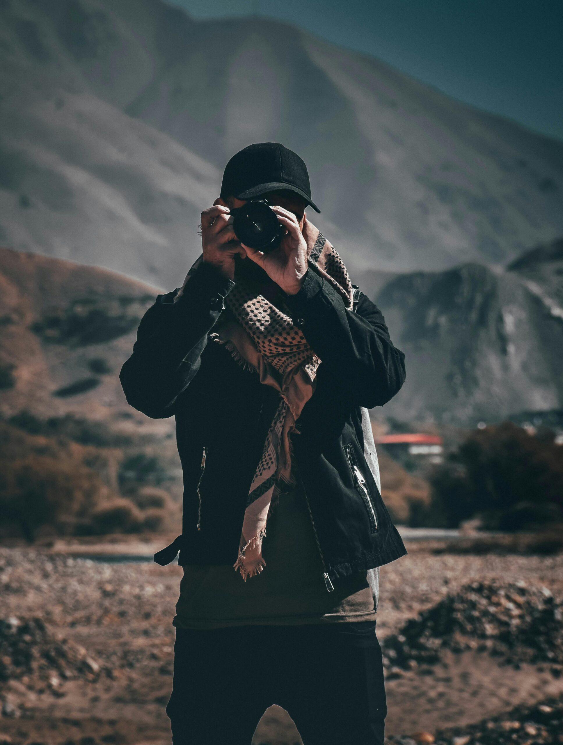 Hiker with a camera capturing a scenic mountain view during a hike