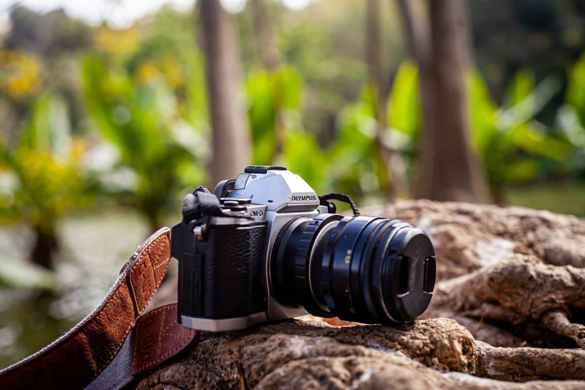 A dusty DSLR camera lying on a rocky surface in nature.