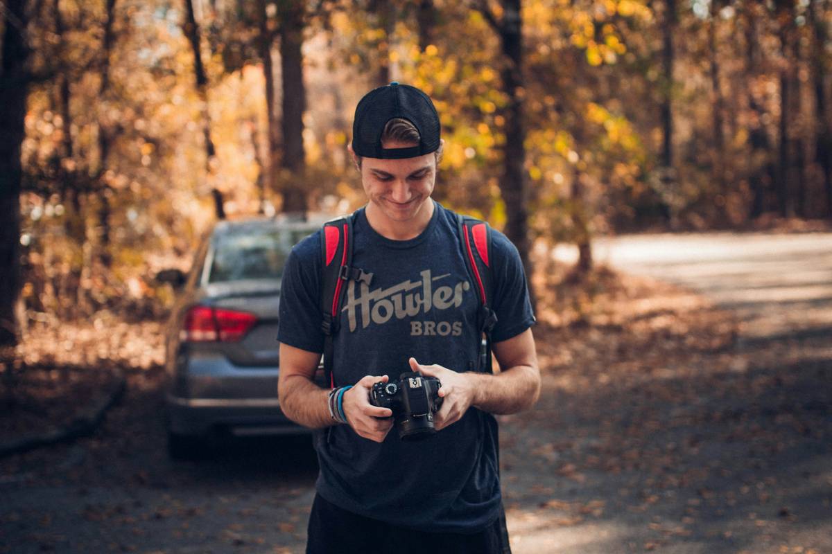 A hiker holding a compact camera on a scenic trail