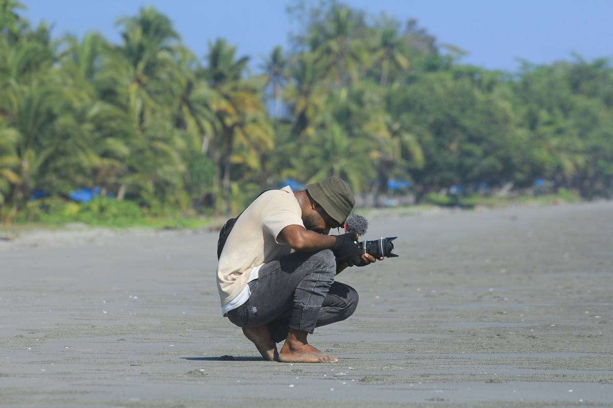 Close-up shot of a trail camera secured on a sturdy branch, angled towards a deer path.