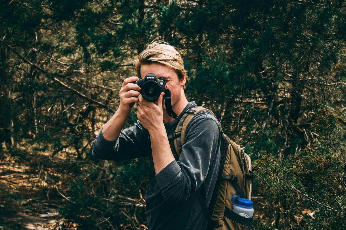 Hiker holding camera with beautiful forest backdrop