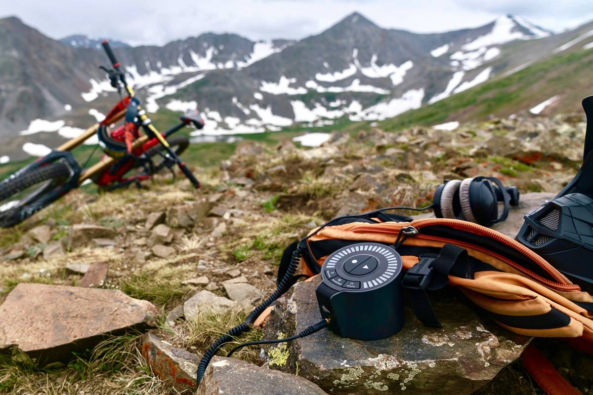 Hiker holding a camera with a natural light lens against scenic mountain backdrop