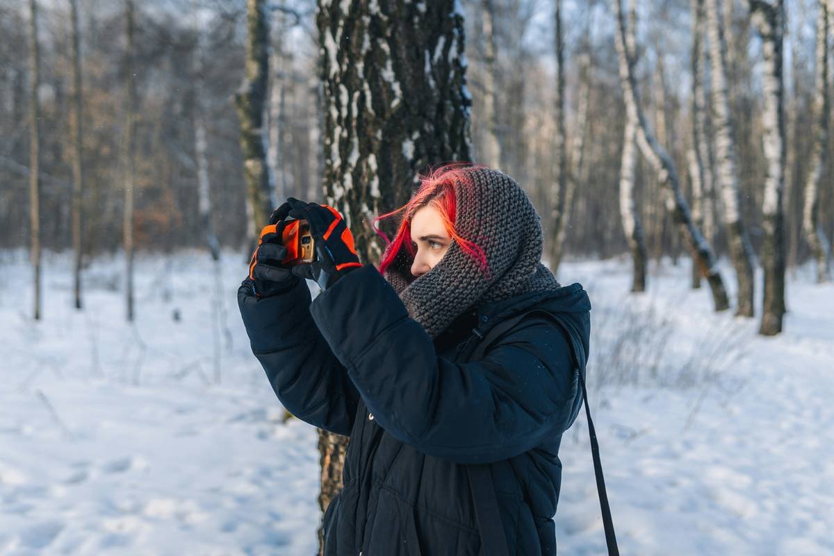 a woman standing in the snow holding a pair of skis