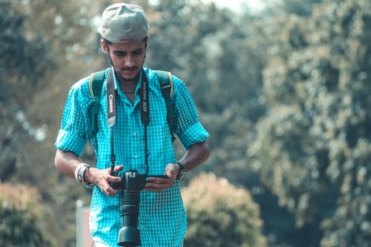 man in red and blue plaid button up shirt holding black dslr camera