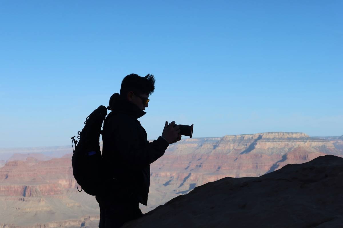 Man photographs the canyon from a high vantage point.