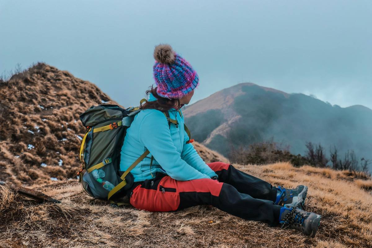 woman sitting on brown soil looking on brown mountain